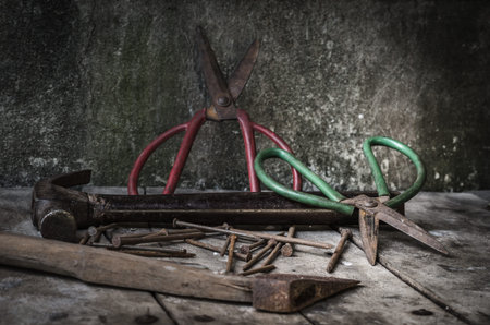 still life with old rusty tools, scissors, hummer and nails on old wooden table backgroundの写真素材