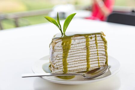 Green tea crepe cake with green tea sauce is on white plateの写真素材