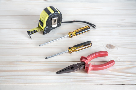 needle-nose pliers, phillips screw driver and tape measure on the wooden backgroundの写真素材