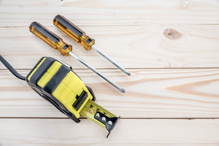 tape measure and phillips screw driver on the wooden backgroundの写真素材