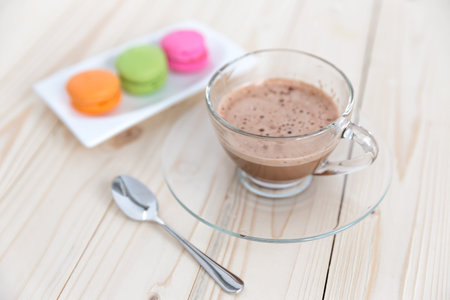 Macaroons with a cup of coffee on a wood background