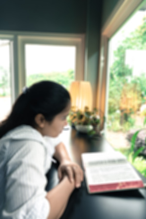 blurred image of a woman reading the holy bible in the church for religion backgroundの写真素材