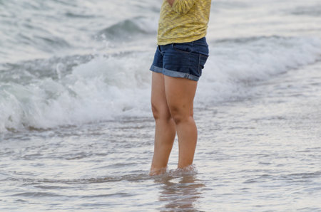 young girl feet on a sandy beach, woman standing on the sand beach,  just her feet and legs showing
