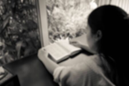 blurred image of a woman reading the holy bible in the church for religion backgroundの写真素材