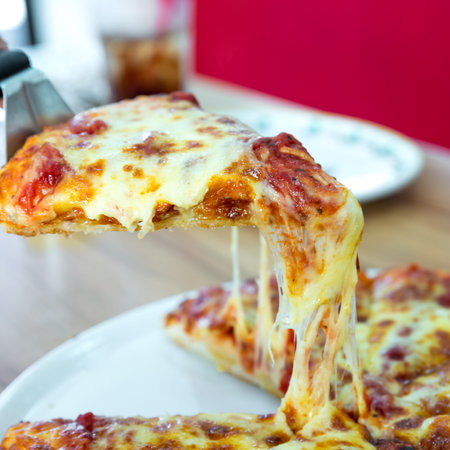 lifted Vegetarian pizza slice with a topping of cheese, mushroom, tomatoesの写真素材