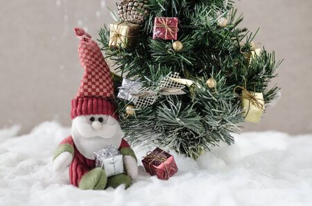 doll of santa claus with christmas tree in snow,cute stuffed toy Santa claus giving a christmas presentの写真素材