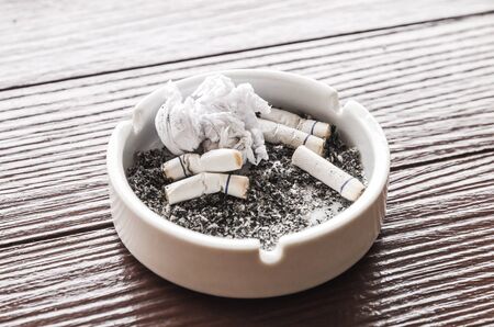 An ashtray with cigarettes and ash, burned cigarettes is in white ashtrayの写真素材