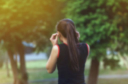 Attractive girl listening to the music while training outdoors - blurred imageの写真素材