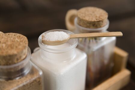 white sugar in wood spoon on sugar containerの写真素材