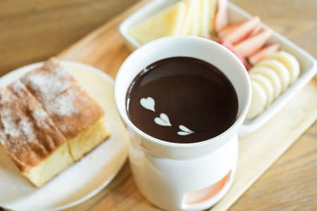 chocolate fondue with fruits assortment on wooden backgroundの写真素材