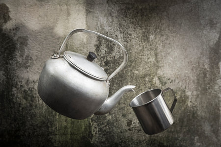 Still life with old rustic aluminum kettle and stainless mug