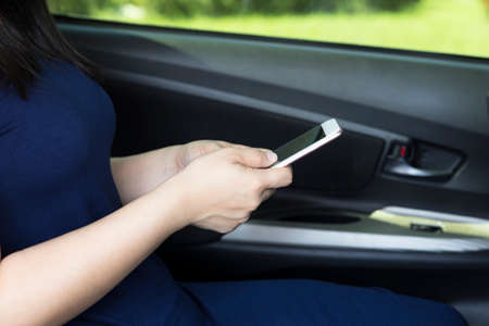 Hand of beautiful woman holding and using smartphone in carの写真素材