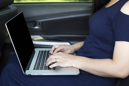 Businesswoman with laptop in a carの写真素材