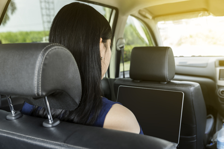 Businesswoman with laptop in a carの写真素材