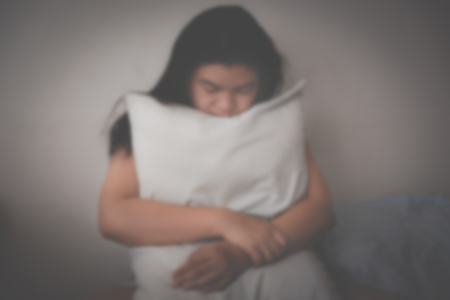 depressed asian woman sitting on bed in room - sadness concept, selective focus and vintage toning, blurryの写真素材