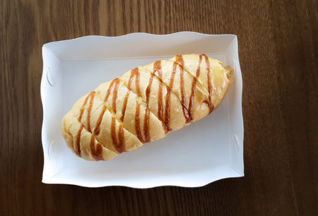 homemade cheese bread in white paper box for take away on wooden table - vegan food