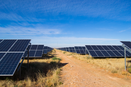 Solar plant on sunny day with blue sky and gravel roadの写真素材