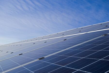 Close-up of solar panel array with blue sky and cloudsの写真素材