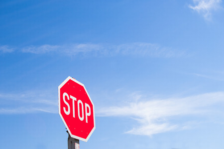 Red stop sign against blue sky on a sunny dayの写真素材