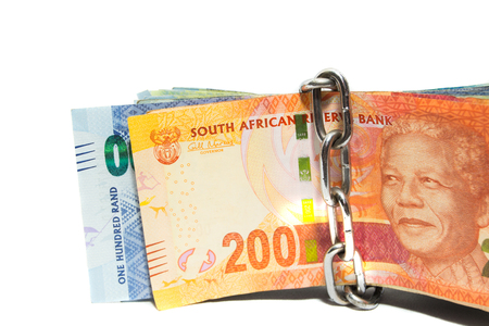 Money safety concept with chains wrapped around foreign rand banknotes on whiteの写真素材