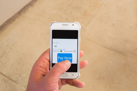On the go payment concept with person doing an online payment on a white smartphoneの写真素材