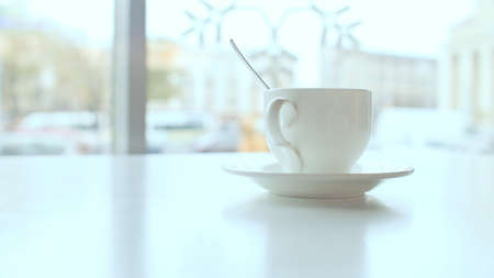 White coffee cup on the table in coffee against a background windowの写真素材