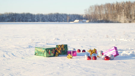 Christmas gifts in a field on snow in a sunny, frosty and clear weather outdoors.の写真素材