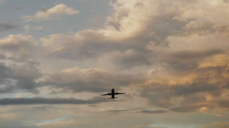 Passenger airplane taking off at sunset against the background of a very beautiful clouds.の写真素材