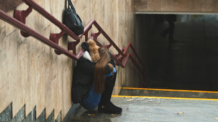 Young girl on the stairs in the subway depressed sitting alone obscures the face with his handsand crying. Autumn.の写真素材