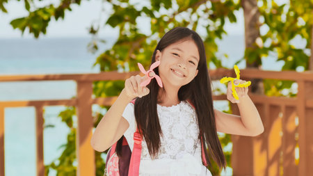 A small filipino schoolgirl shows spinning spinners. Tropical landscape. Summer. Childhood.の写真素材