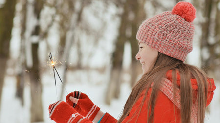 The charming young schoolgirl joyfully holds in her hands a packaged box with a gift in the winter...