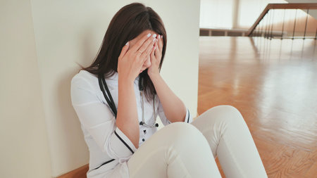 Young girl doctor cries sitting on the floor of the hospital.