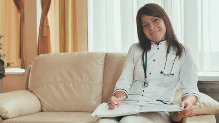 A young woman doctor writes in a summary in a good mood.の写真素材