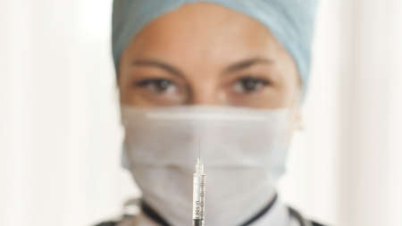 A woman doctor prepares a syringe for a shot.の写真素材