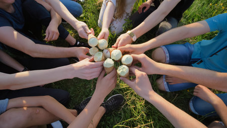 Nine friends clink glasses of ice cream. Hands close-up.