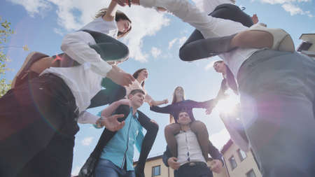 The girls sit on the shoulders of the guys and hug together. Happy friends are senior pupils.の写真素材
