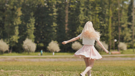 A happy young russian girl is running in the city park.の写真素材