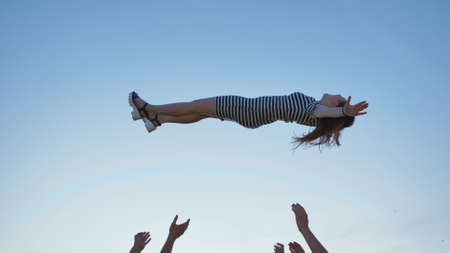 Friends of schoolchildren throw up a girl at sunset.の写真素材