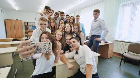 Young happy cheerful students making selfie in school class.
