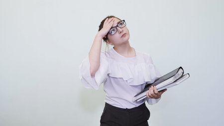 A schoolgirl in glasses depicts a successful girl with notes. A student depicts a reverie. The solution of the problem.の写真素材