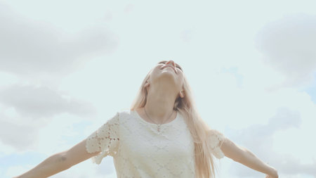 Young Russian girl blonde posing against a white sky on a summer day.