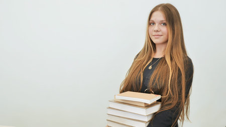 A schoolgirl in a good mood with a pile of books.