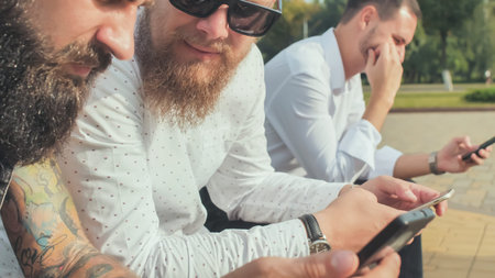 Three brutal bearded men use their phones.の写真素材
