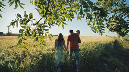 A young family with children goes to the field in the evening warm weather.
