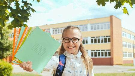 Portrait of a smiling schoolgirl showing notebooks and rulers. Happy start of the school year.