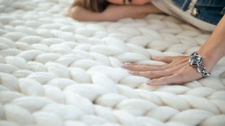 The girl is stroking the merino white plaid. Hand close-up.の写真素材