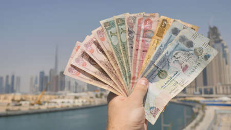 A man holds in his hand the money of the Arab Emirates. Hand close-up.の写真素材