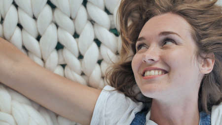 A young girl lies on a merino white blanket in the park and enjoys the summer weather.の写真素材
