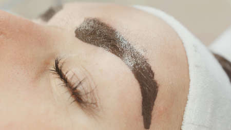 Permanent makeup. Permanent tattooing of eyebrows. Cosmetologist applying permanent make up on eyebrows- eyebrow tattoo.の写真素材