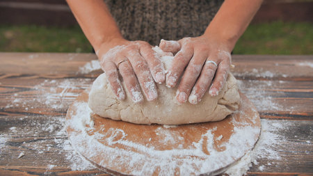 A young woman kneads the dough with her hands. Homemade bread baking